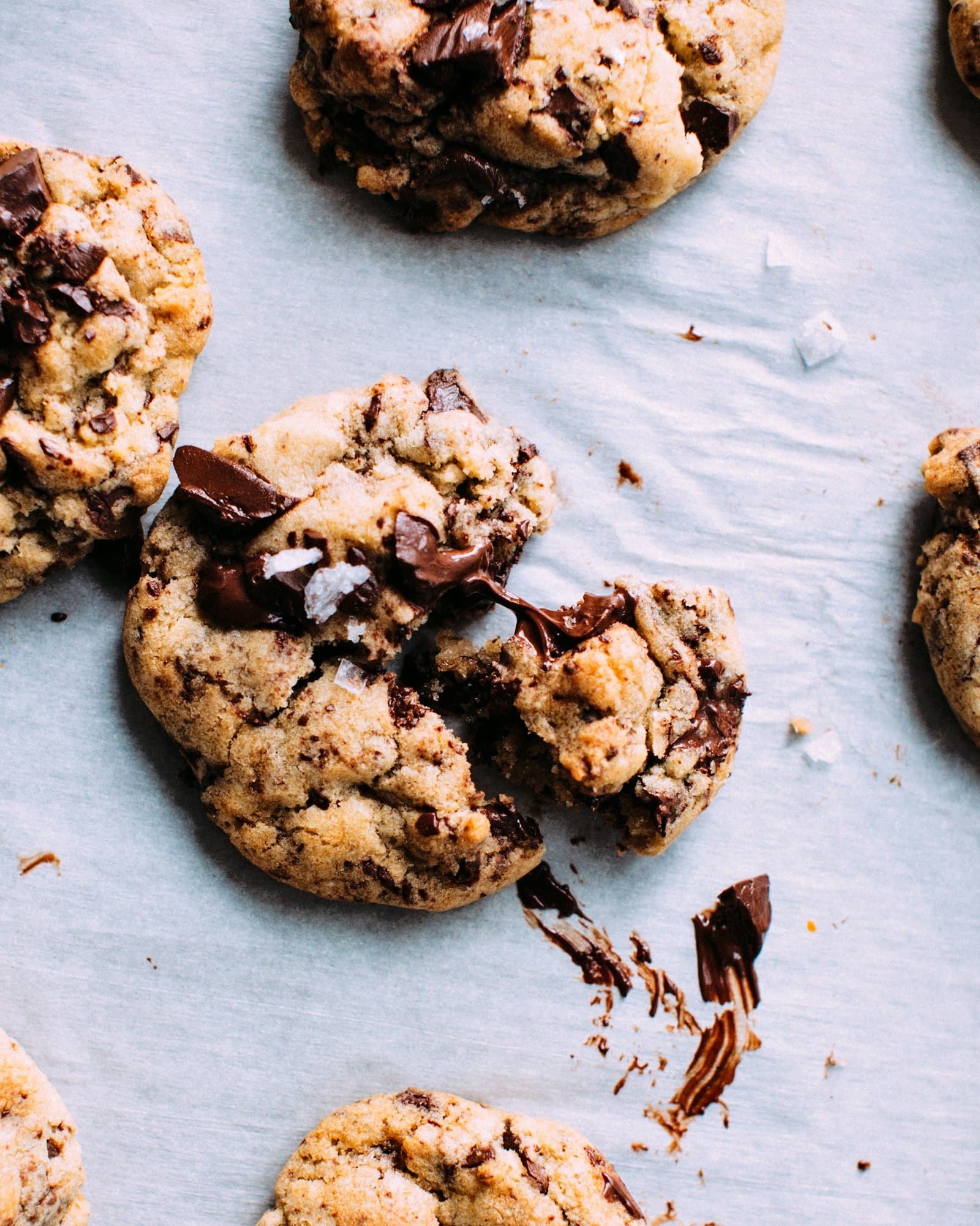 Overhead of gooey chocolate-chunk cookies with melting chocolate and flaky salt.